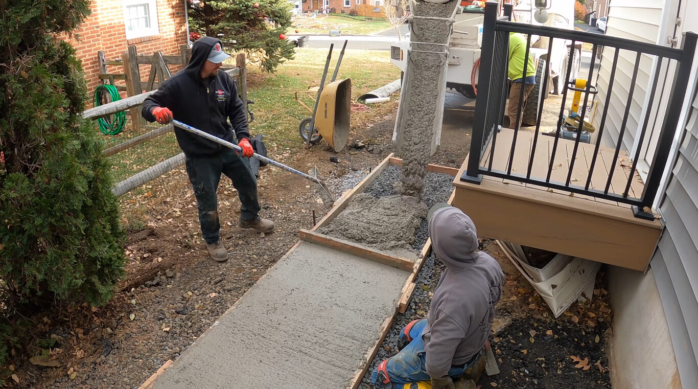 Precision concrete walkway installation with proper grading and base